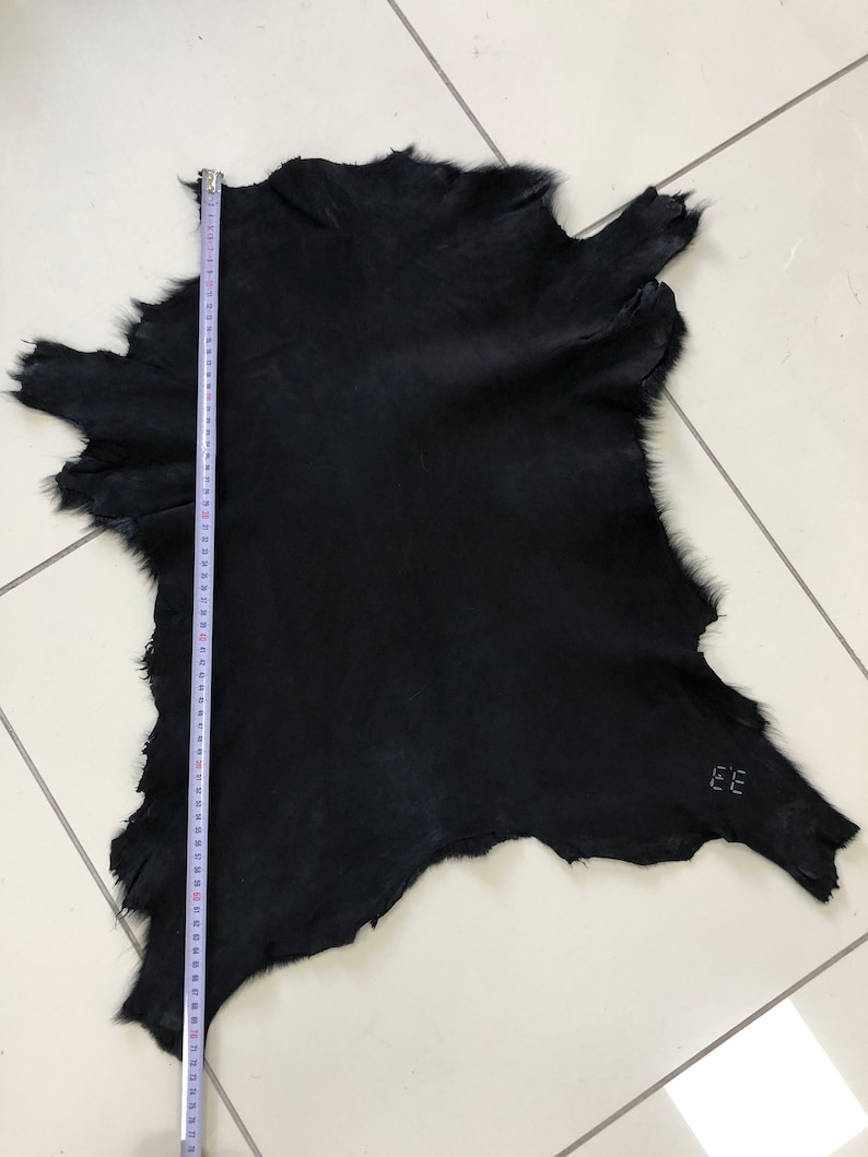 May include: A black fur hide with a measuring tape next to it. The hide is approximately 28 inches long. The hide has a label that says "EE".