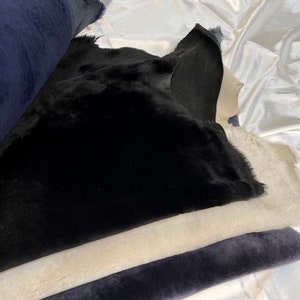 May include: A stack of fabric swatches in black, beige, and dark blue. The fabric is soft and plush, with a fuzzy texture.