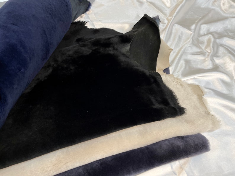 May include: A stack of fabric swatches in black, beige, and dark blue. The fabric is soft and plush, with a fuzzy texture.