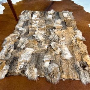 May include: A patchwork rug made from multiple pieces of brown and tan animal fur. The fur is arranged in a grid pattern and has a soft, fluffy texture.