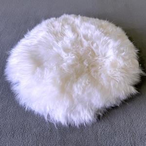 May include: A white fluffy round rug made of faux fur. The rug is soft and plush, perfect for adding a touch of luxury to any room.