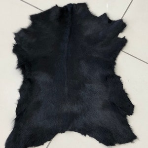 May include: A black cowhide rug with a soft, fuzzy texture.