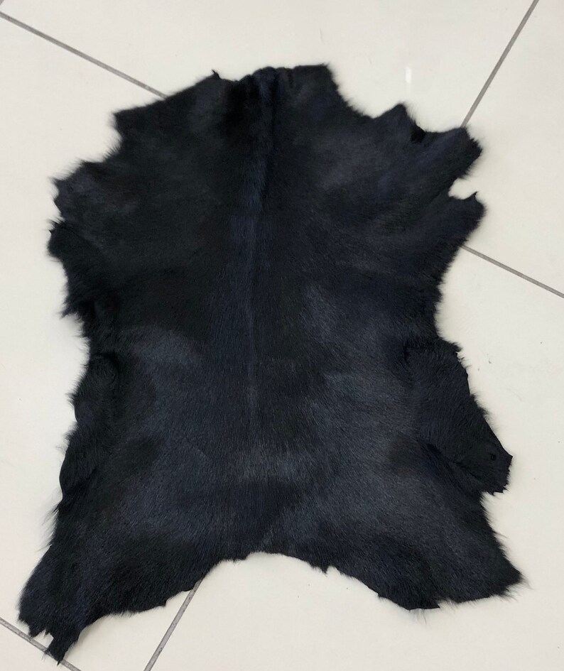 May include: A black cowhide rug with a soft, fuzzy texture.