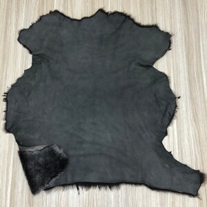 以下が含まれることがあります： 柔らかくふわふわした質感の濃いグレーの毛皮。毛皮は縁がトリミングされており、滑らかで革のような裏地があります。