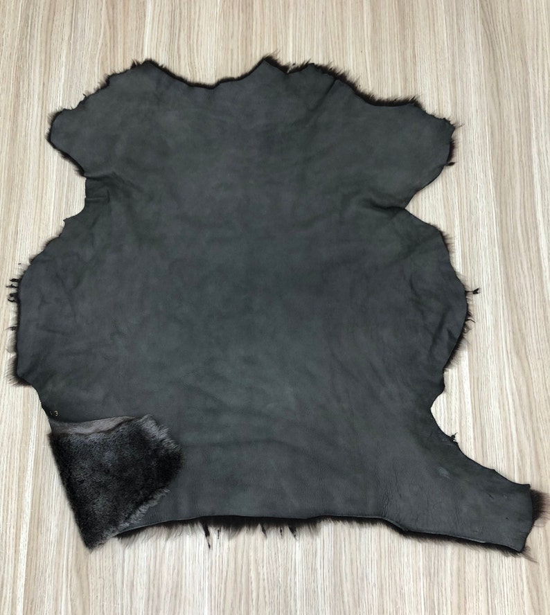 以下が含まれることがあります： 柔らかくふわふわした質感の濃いグレーの毛皮。毛皮は縁がトリミングされており、滑らかで革のような裏地があります。