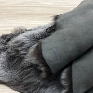 以下が含まれることがあります： 柔らかくふわふわした毛皮面と、滑らかなスエードのような革面を持つ、灰色の羊の皮の1枚
