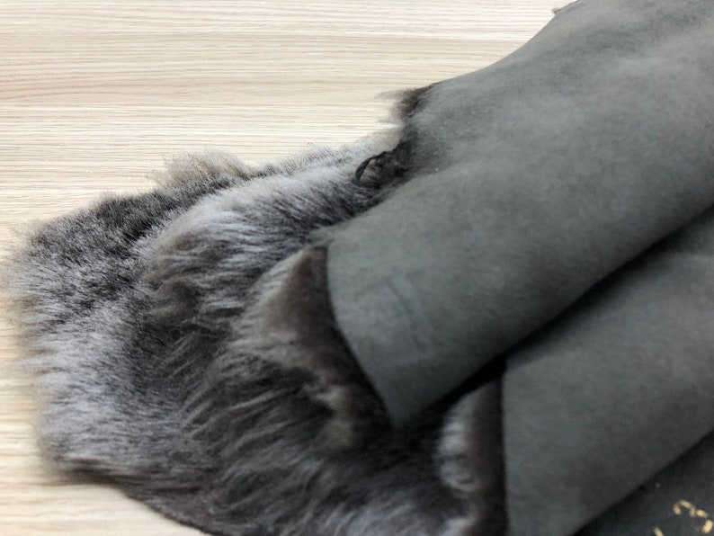 以下が含まれることがあります： 柔らかくふわふわした毛皮面と、滑らかなスエードのような革面を持つ、灰色の羊の皮の1枚