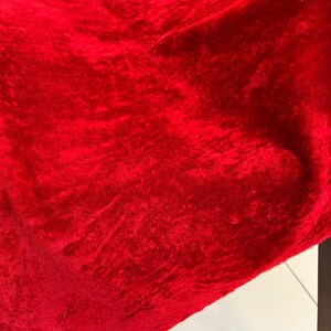 Peut inclure: Un gros plan sur un tissu de velours rouge fonc&eacute; avec une surface textur&eacute;e.