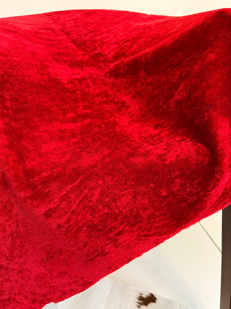 Peut inclure: Un gros plan sur un tissu de velours rouge fonc&eacute; avec une surface textur&eacute;e.
