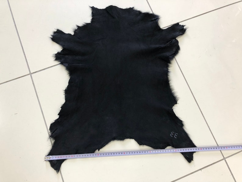 May include: A black fur pelt with a measurement tape showing it is approximately 30 inches wide.
