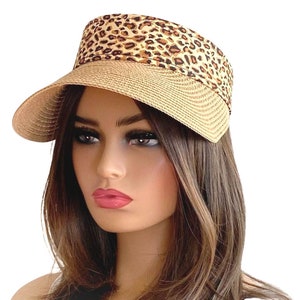 May include: A straw sun visor with a leopard print fabric band. The visor is beige and the band is brown with black spots.