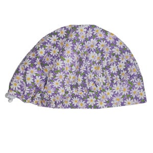 a purple and white hat with daisies on it