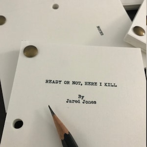 May include: A white script cover with brass brads. The title "READY OR NOT, HERE I KILL" is printed in black font. Below the title is "By Jared Jones".