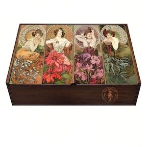 Peut inclure: Une boîte en bois foncé avec un couvercle décoratif. Le couvercle présente quatre panneaux Art nouveau, chacun représentant une femme avec des éléments floraux orange, rouge, violet et vert. La boîte est de couleur marron foncé.