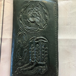 May include: Black leather wallet with an embossed design of a horse head inside a horseshoe and a cowboy boot.