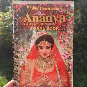 May include: A spiral bound notebook with a cover featuring a woman in a red and gold bridal outfit. The text on the cover reads "Ye Rista Kya Kehlata Hai Ananya Kumkum Bindi Spiral Book".
