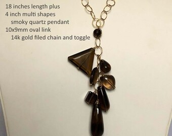 May include: A gold chain necklace with a smoky quartz pendant. The pendant is made up of multiple brown, faceted stones of different shapes and sizes. The chain is 18 inches long with a 4 inch drop. The chain is 14k gold filled. 18 inches length plus 4 inch multi shapes smoky quartz pendant 10x9mm oval link 14k gold filled chain and toggle