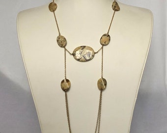 May include: A gold chain necklace with a long, layered design. The necklace features multiple oval-shaped feldspar stones in a light brown and white color. The necklace is 34 inches long and is made of 14k gold filled chain.
