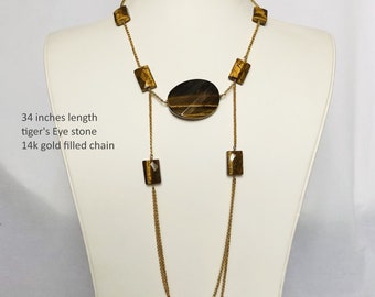 May include: A gold-filled chain necklace with a tiger's eye stone pendant and rectangular tiger's eye stones. The necklace is 34 inches long.