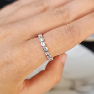 May include: A silver band ring with a row of small, clear gemstones.