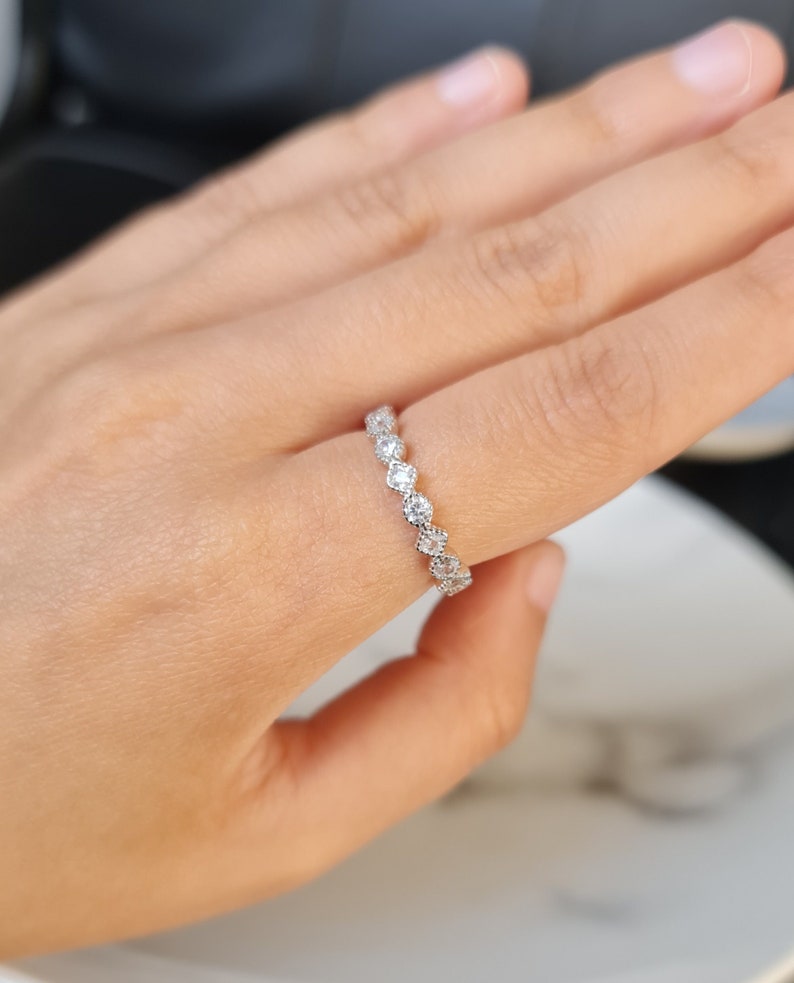 May include: A silver band ring with a row of small, clear gemstones.