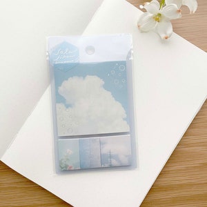 May include: A pack of blue and white patterned sticky notes with a cloud and bubbles design. The pack is labelled "Sola: ilhan" in a handwritten font.