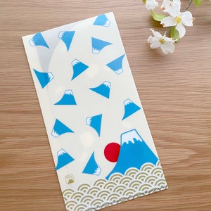 May include: A white plastic folder with a blue and white mountain pattern. The folder has a gold wave pattern at the bottom and a red sun in the top right corner. The text "Mt. Fuji" is printed in the bottom left corner.
