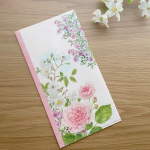 May include: A pink and white floral envelope with a pink border. The envelope features a delicate floral design with pink and white roses and green leaves.