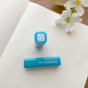 May include: A blue and white Pilot FriXion Stamp with a pot design. The stamp is in a plastic case with the text "Pilot FriXion Stamp" on the side.