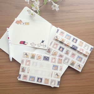 May include: Three blank cards with bunny rabbit illustrations. The cards are decorated with a repeating pattern of bunnies in different poses, flowers, and postage stamps. The cards are perfect for sending a handwritten note.