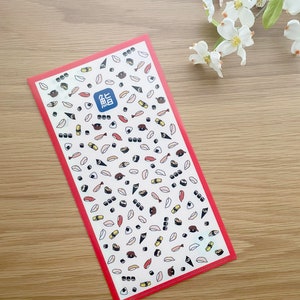 May include: A red plastic folder with a white background and a repeating pattern of various sushi rolls. The text "鮨" is printed in blue on the folder.