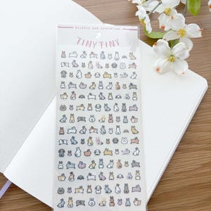 May include: A sheet of Tiny Tiny stickers featuring various bunny illustrations in pastel colors. The stickers are in a clear plastic package, with the text "Relaxed and Comforting" and "We are Usagi". The stickers are on a white dotted notebook.