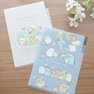 May include: Two clear plastic folders with colourful illustrations of cartoon characters. The folders have the text "Sumikkogurashi Drawing" on them.