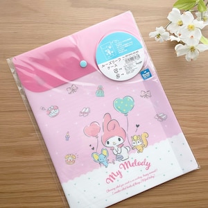May include: A pink plastic folder with a clear front and a My Melody design. The folder has a blue button closure and a pocket on the front. The text on the folder reads "My Melody" and "Choning what you sound is an acting happy moment!! I wonder what hinks of things I'll find today?"