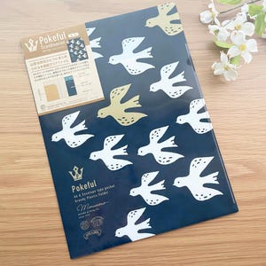May include: A navy blue plastic folder with a pattern of white and gold birds in flight. The folder has text that reads "Pokeful" and "A4 & Envelope type packet Greedy Plastic Folder".