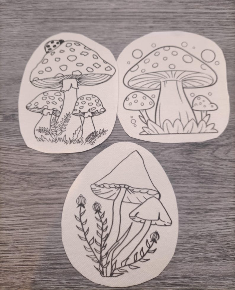 K&ouml;nnte beinhalten: Drei Schwarzwei&szlig;-Zeichnungen von Pilzen auf wei&szlig;em Papier. Die Pilze sind detailliert gezeichnet und haben einen verspielten Charakter.