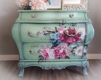 May include: A green painted antique chest of drawers with ornate floral designs and silver handles. The drawers are decorated with a vintage postcard design and the text "Carte Postale".