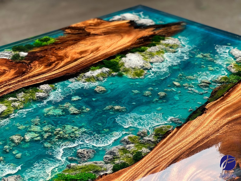 K&ouml;nnte beinhalten: Nahaufnahme einer Tischplatte aus Holz mit einer in Epoxidharz eingebetteten Flussszene. Der Fluss ist in einem leuchtenden T&uuml;rkisblau mit wei&szlig;em Schaum und Steinen gehalten. Das Holz ist in einem satten Braun mit dunklen Streifen.
