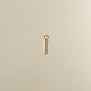 Peut inclure: Un charme de barre en or avec des pierres de zircone cubique transparentes.