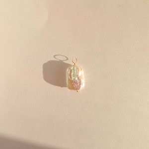 May include: A white baroque pearl pendant with a gold-toned metal loop.