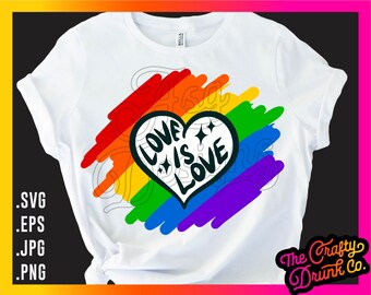 Puede incluir: Una camiseta blanca con un diseño de corazón arcoíris. El corazón tiene el texto "Love is Love" en su interior. El arcoíris está hecho de pinceladas.