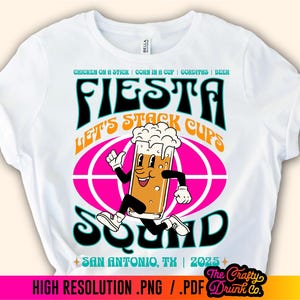May include: White t-shirt with a colorful graphic design featuring a cartoon beer mug running with the text "Fiesta Let's Stack Cups Squad" and "San Antonio, TX | 2025".