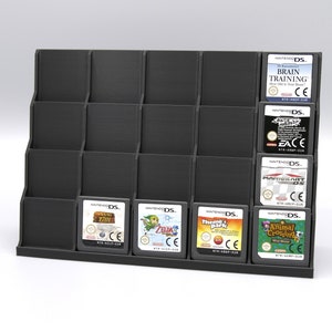 May include: A black plastic stand with 18 slots for storing Nintendo DS game cartridges. The stand is filled with various game cartridges, including "Brain Training", "Animal Crossing", "Zelda", and "7701".