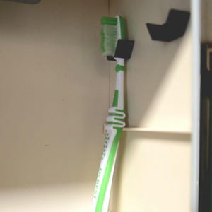 Toothbrush holder, adhesive and space-saving