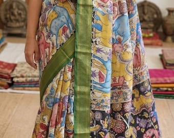 May include: A colorful saree with a detailed pattern featuring elephants, figures, and floral designs. The saree has a green border and the text "Parovarya" is visible. The fabric is draped, showcasing the intricate artwork.