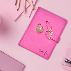 May include: Pink diary with a heart-shaped lock and key, the name Jennifer is written on the cover.