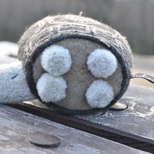 May include: A gray and white plush turtle toy with a soft, fuzzy texture. The turtle has four white, fluffy spots on its shell.