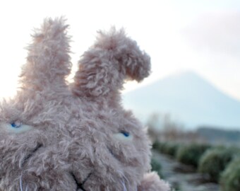 May include: A plush toy rabbit with soft, fluffy fur in a light pink color. The rabbit has large, blue eyes and a long, floppy nose.