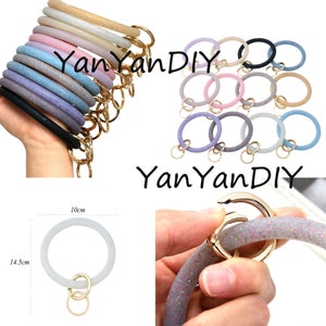 May include: Assortment of 10 colorful silicone keychains with glitter. Each keychain is a 10 cm diameter ring with a gold metal key ring. The keychains are in various colors, including pink, purple, blue, and beige. YanYanDIY is printed on the image.