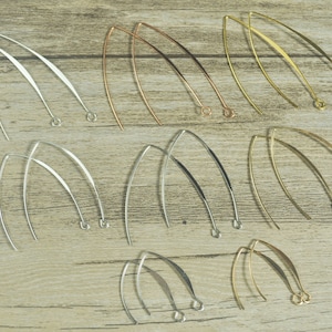 May include: A set of 12 earring findings in three different finishes: gold, silver, and rose gold. The findings are made of thin, curved wire and have a simple, elegant design.